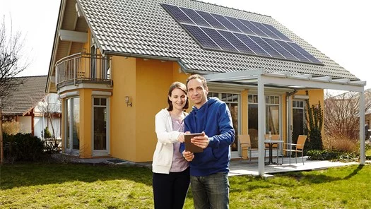 Paar vorm Eigenheim mit Solarpaneel am Dach