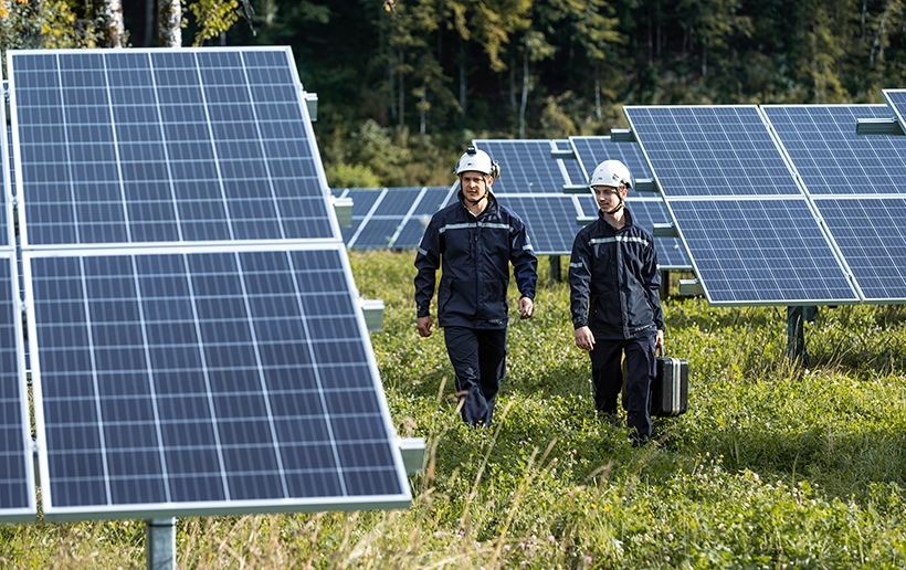 Two VERBUND employees inspect a photovoltaic system in the countryside.