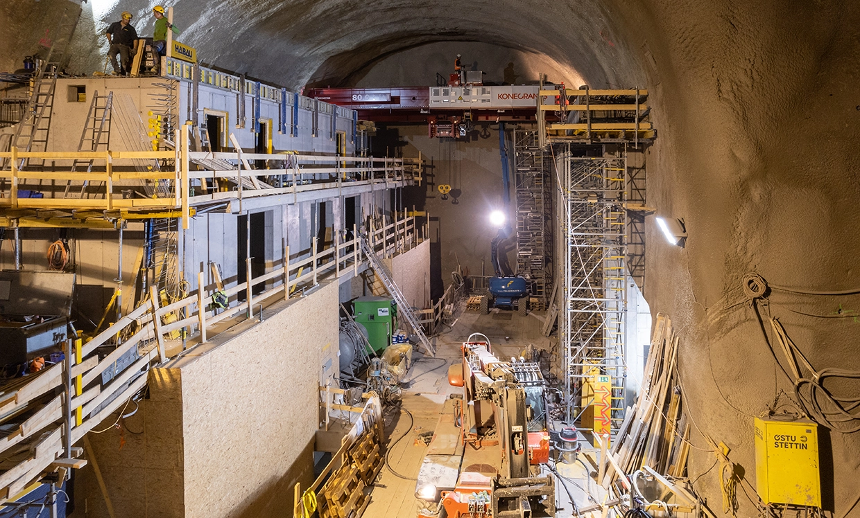 A view of the construction site at the Reisseck two power station. We see a well-lit tunnel with many wooden structures, machines and people.