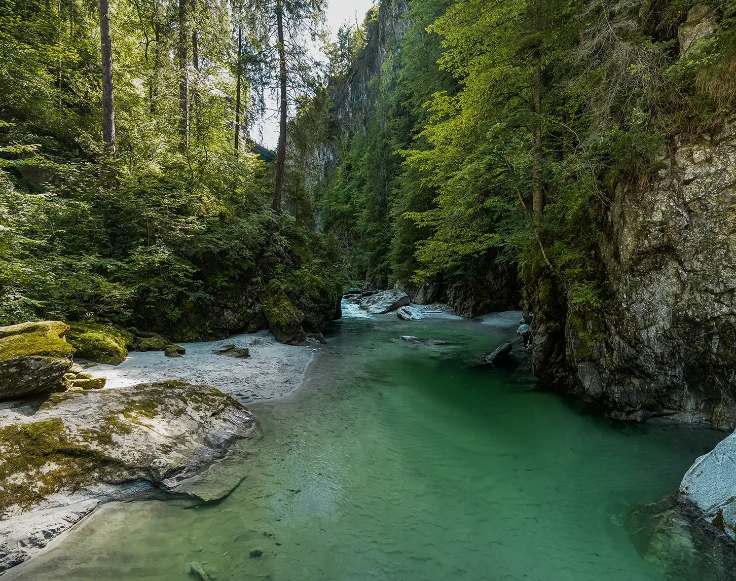 We look out over a mountain river in Schlegeis. The turquoise water is crystal clear. Stone walls and forests rise up to the right and left.
