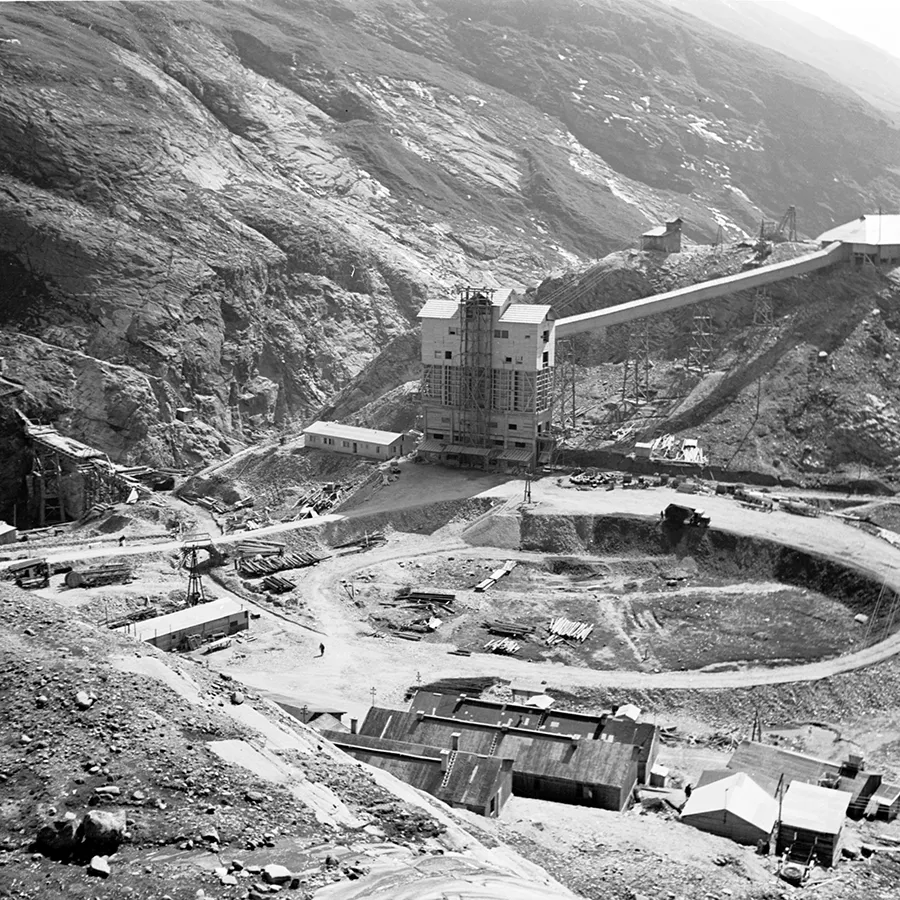 A black-and-white photo depicting a mining site in a rocky environment.