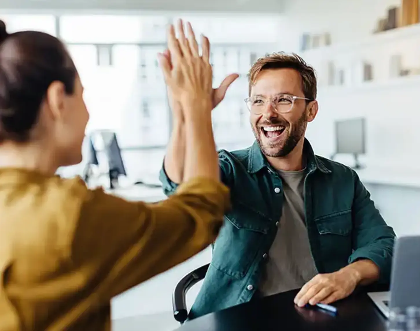 Ein Mann gibt einer jungen Frau während eines Meetings ein High Five.