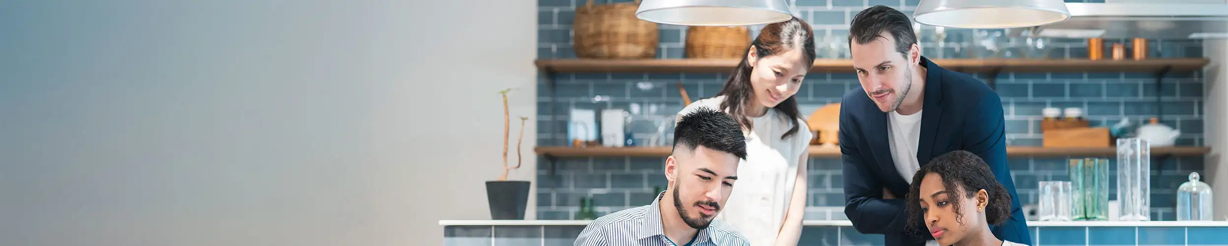 Eine Gruppe von Personen arbeitet gemeinsam an einem Tisch in einem modernen Raum, umgeben von stilvollen Deko-Elementen im Hintergrund.