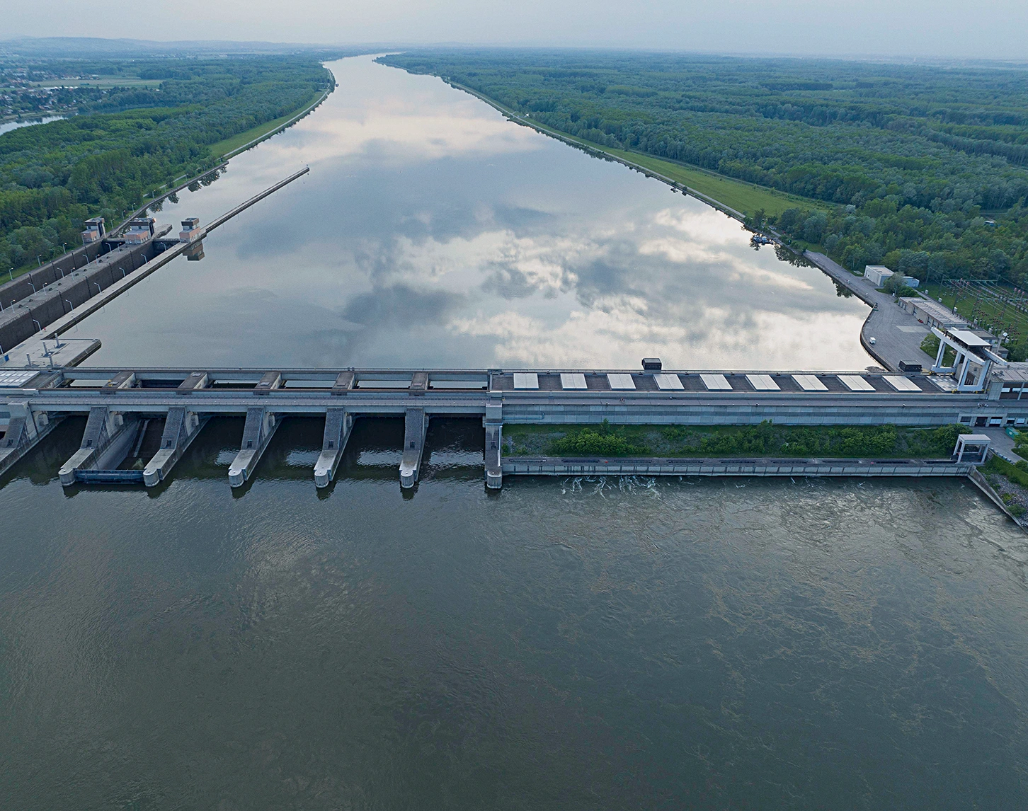 Aerial image of a run-of-river plant, the mighty river sparkles in the sunlight.
