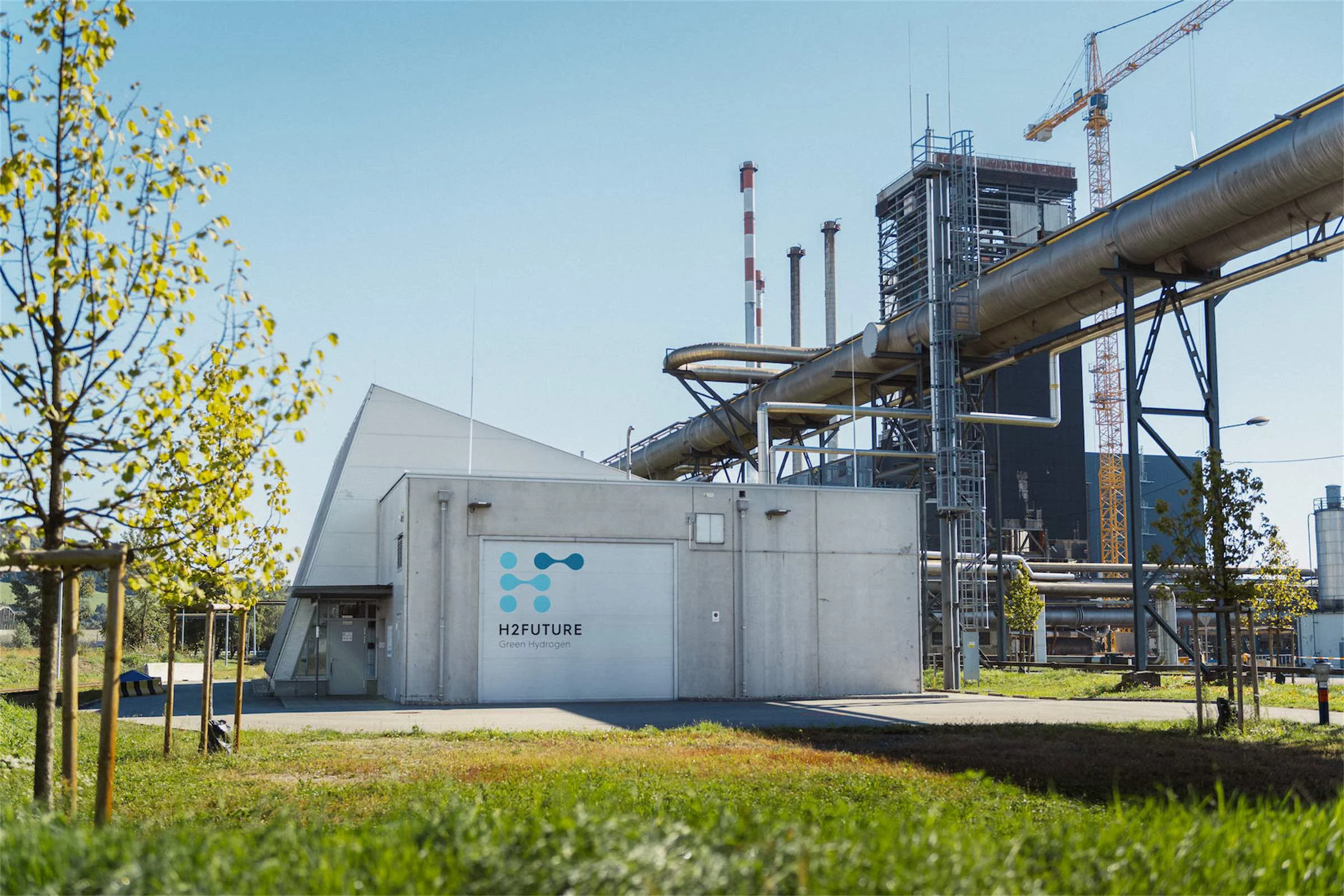 A green lawn in the foreground, in the background a concrete container with a sign "H2Future"