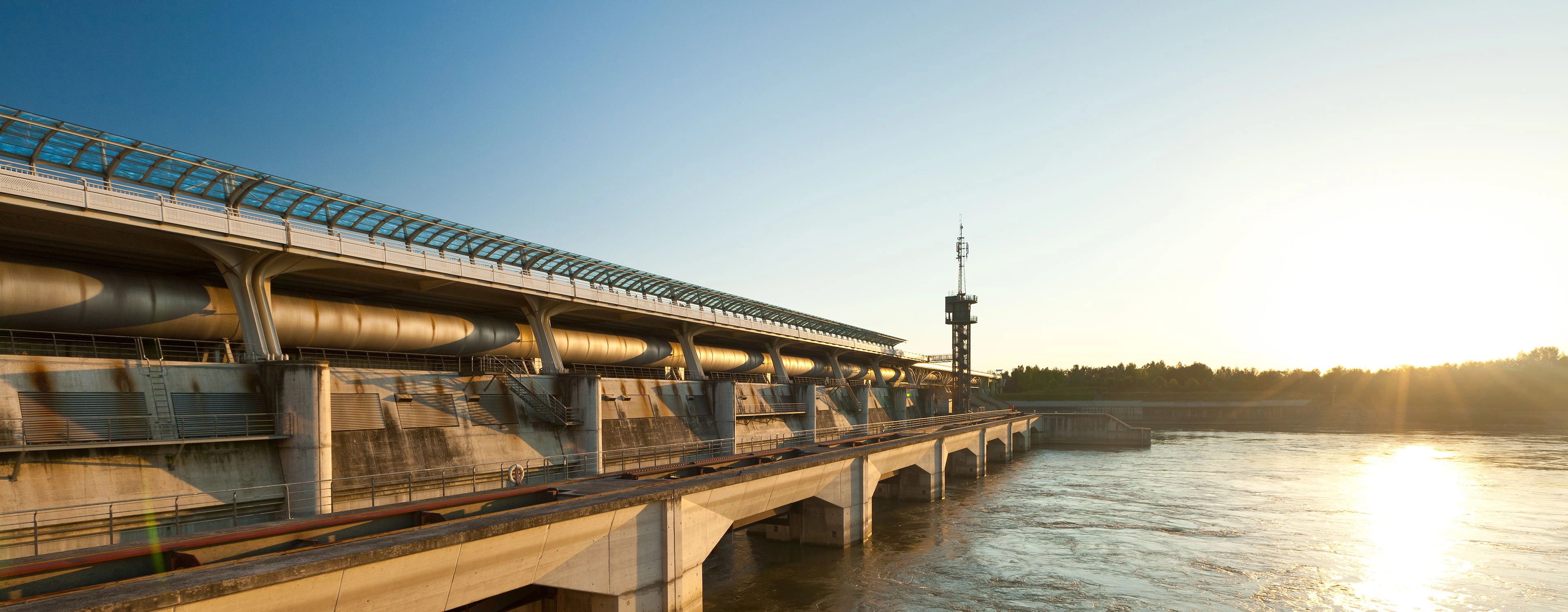 We are looking at the Donaukraft Freudenau near Vienna. The sun is just setting and is reflected in the water.