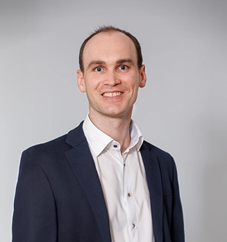 Harald Ott trägt einen Anzug. Er blickt in die Kamera und lächelt.