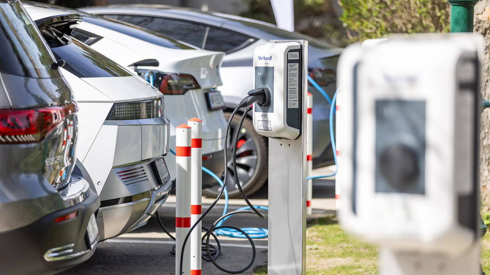 Ein Hotelparkplatz eines Hotels mit mehreren Ladeplätzen, wo verschiedene E-Autos an der Ladeinfrastruktur aufgeladen werden.