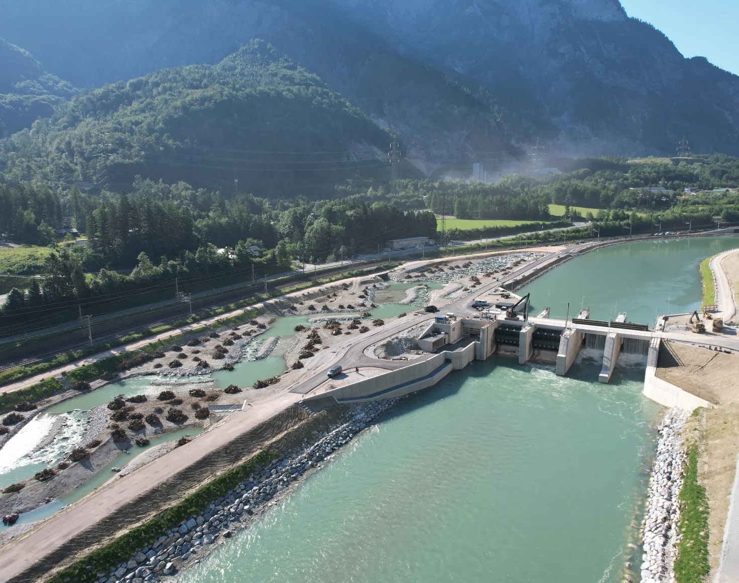 The drone image shows the Stegenwald power station after completion. On the left-hand side, we can see the natural fish migration aid with a road, forest and hill.