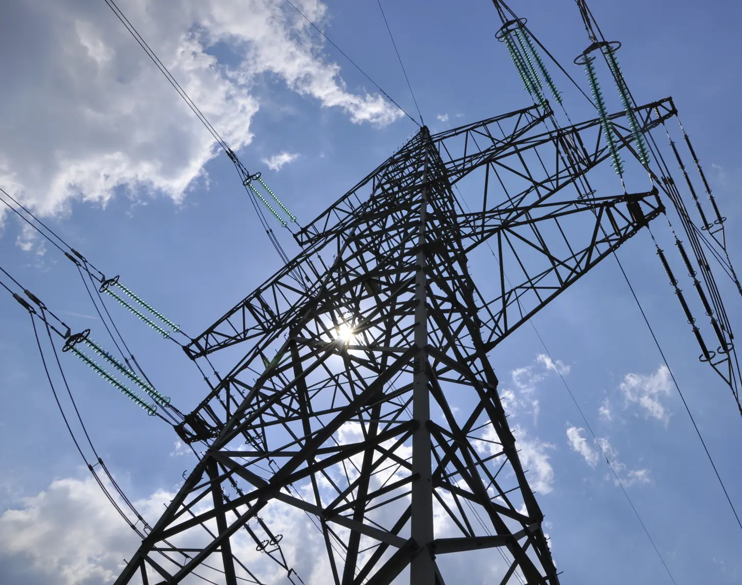 Wir blicken hinauf auf einen Stromleitungsmast.