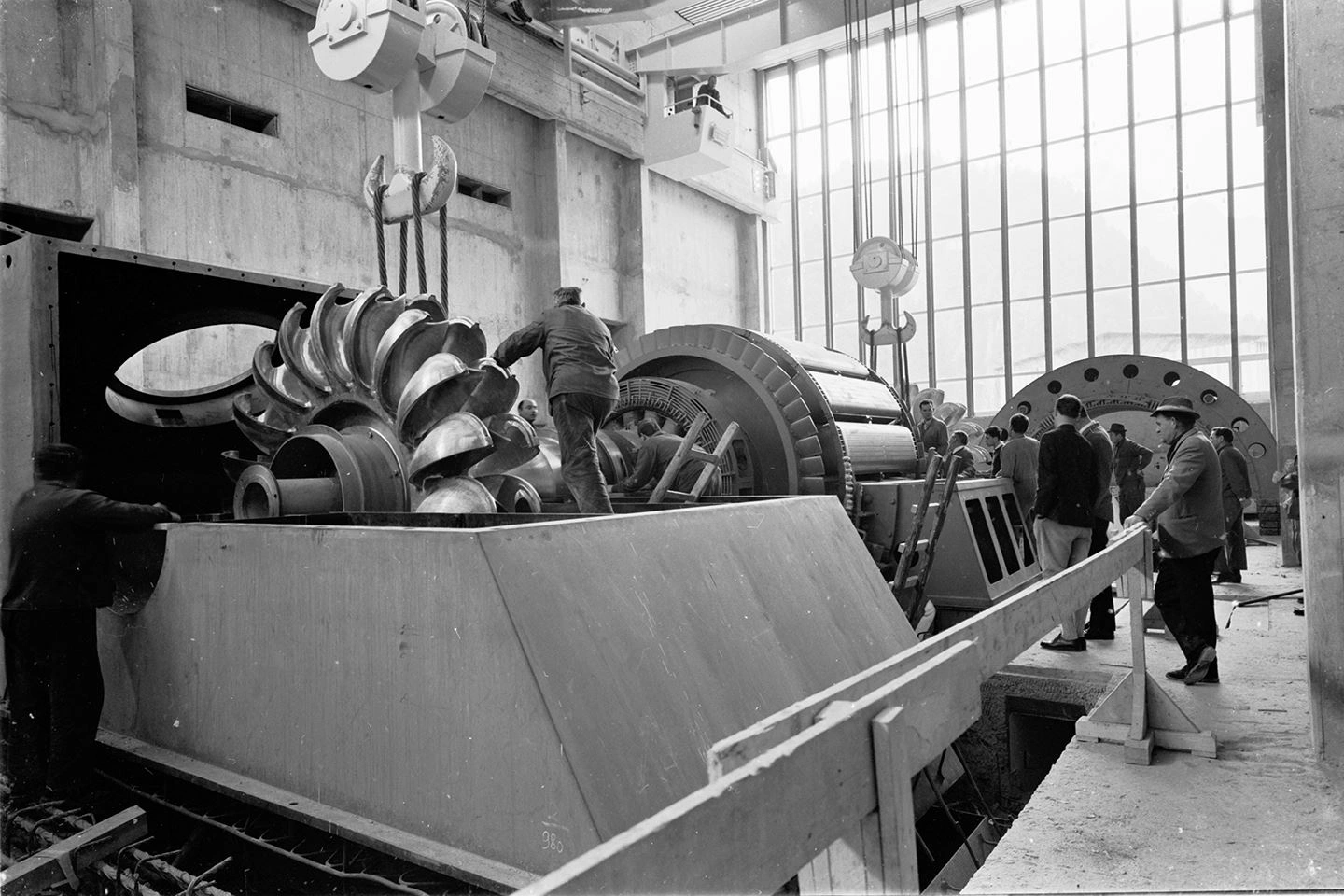 This is a historical photo of the inside of the Mayrhofen power station in the Zillertal valley. Employees are standing in the hall where the turbines are being installed