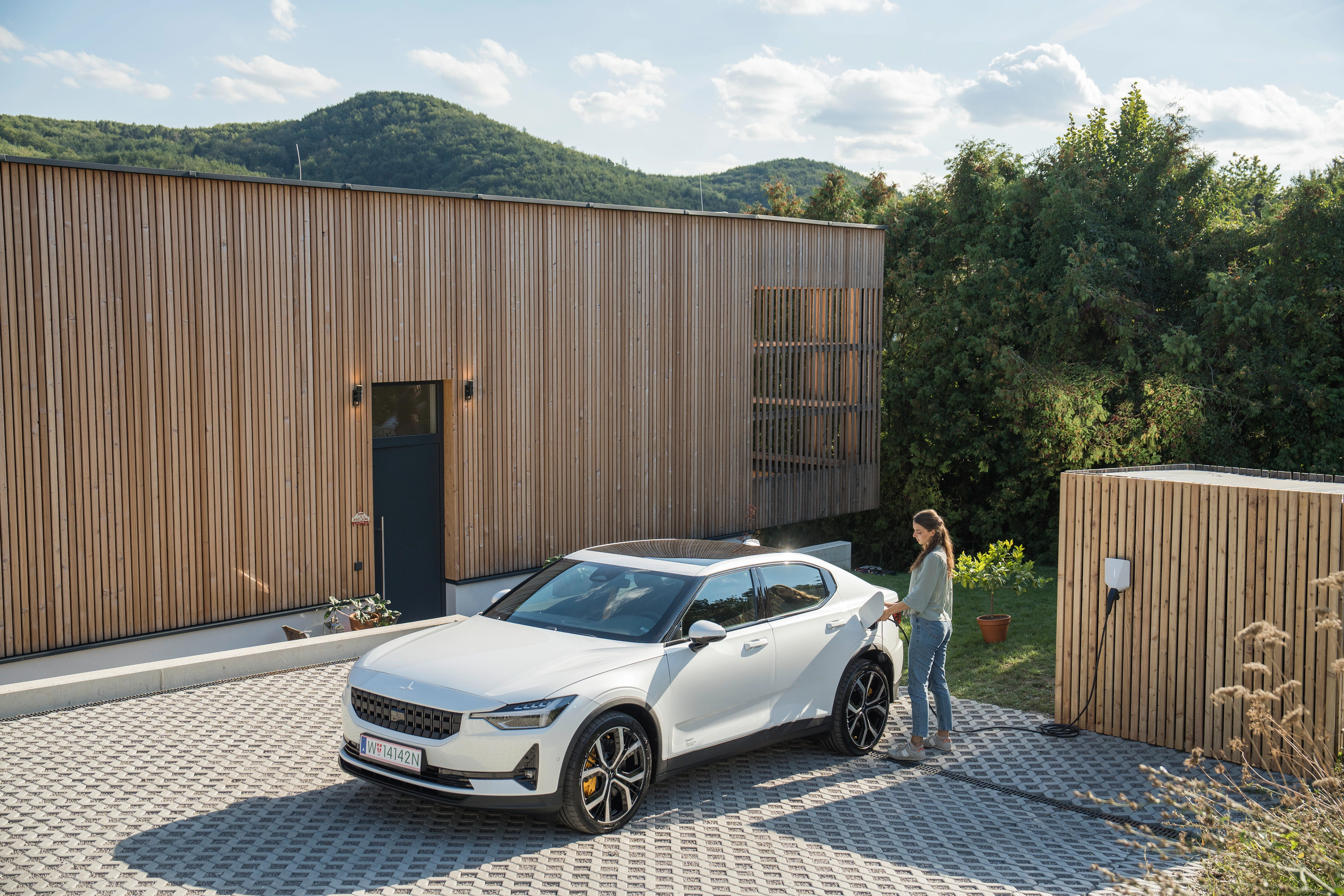 A woman connecting her white electric car to a wallbox charger.