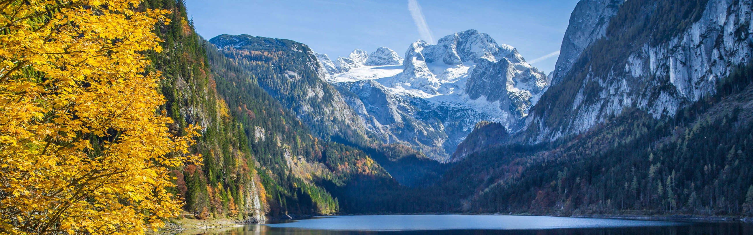 Wir blicken auf schneebedeckte Berge und einen See, der den Himmel widerspiegelt.