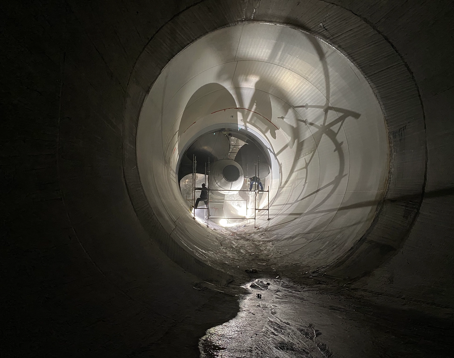 The picture shows the turbine of the Altenwörth run-of-river power plant during inspection. The entire picture is dark and employees are working on the turbine.