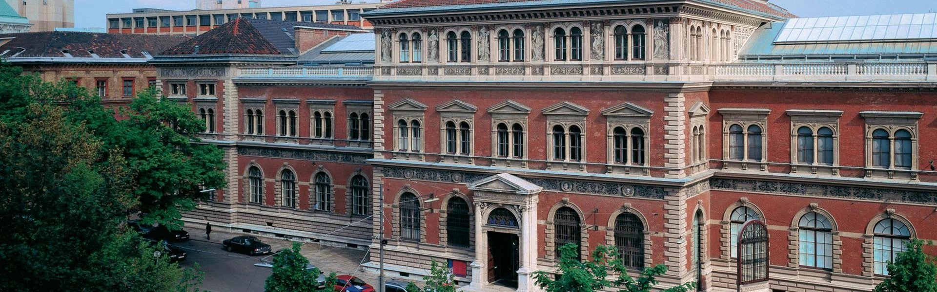 Ein Foto von einem großen Backsteingebäude mit Rundbogenfenstern und Solarpanels auf dem Dach.