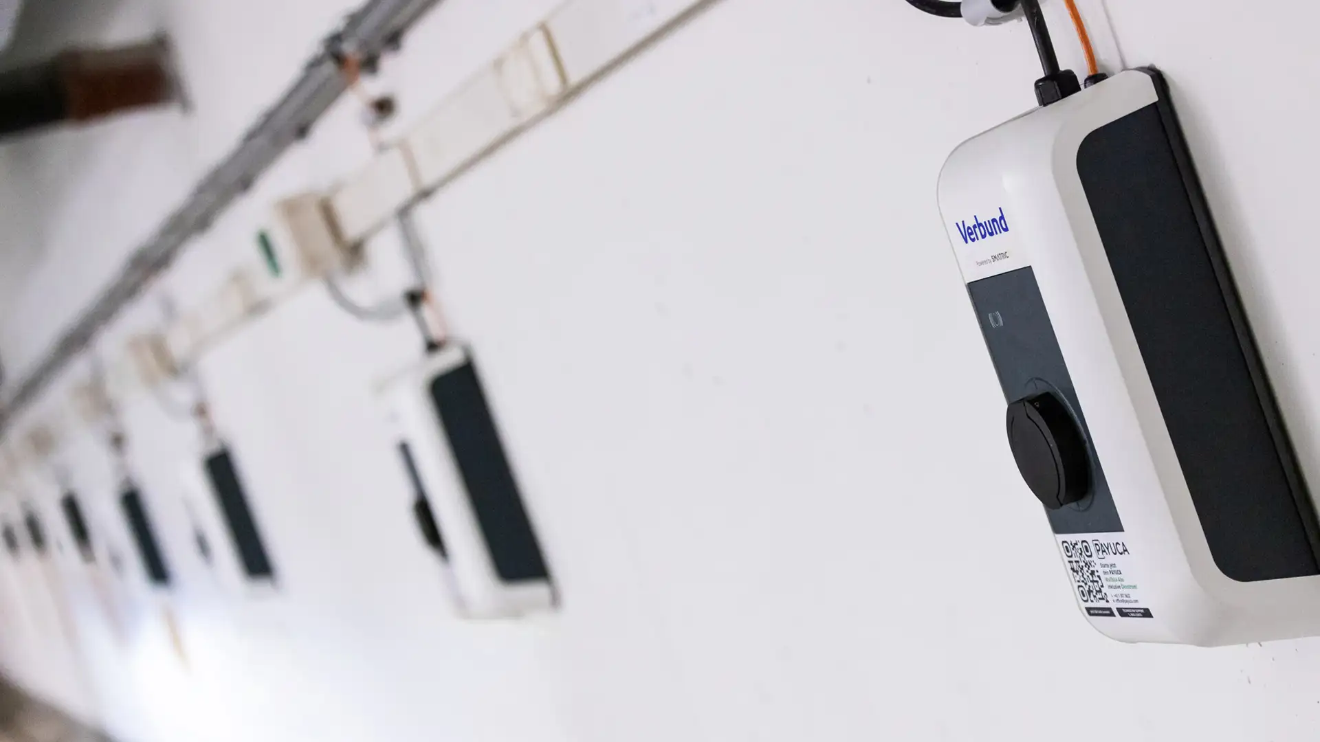 Eine lange Wand in einer Parkgarage, mit multiplen Ladepunkten von VERBUND.