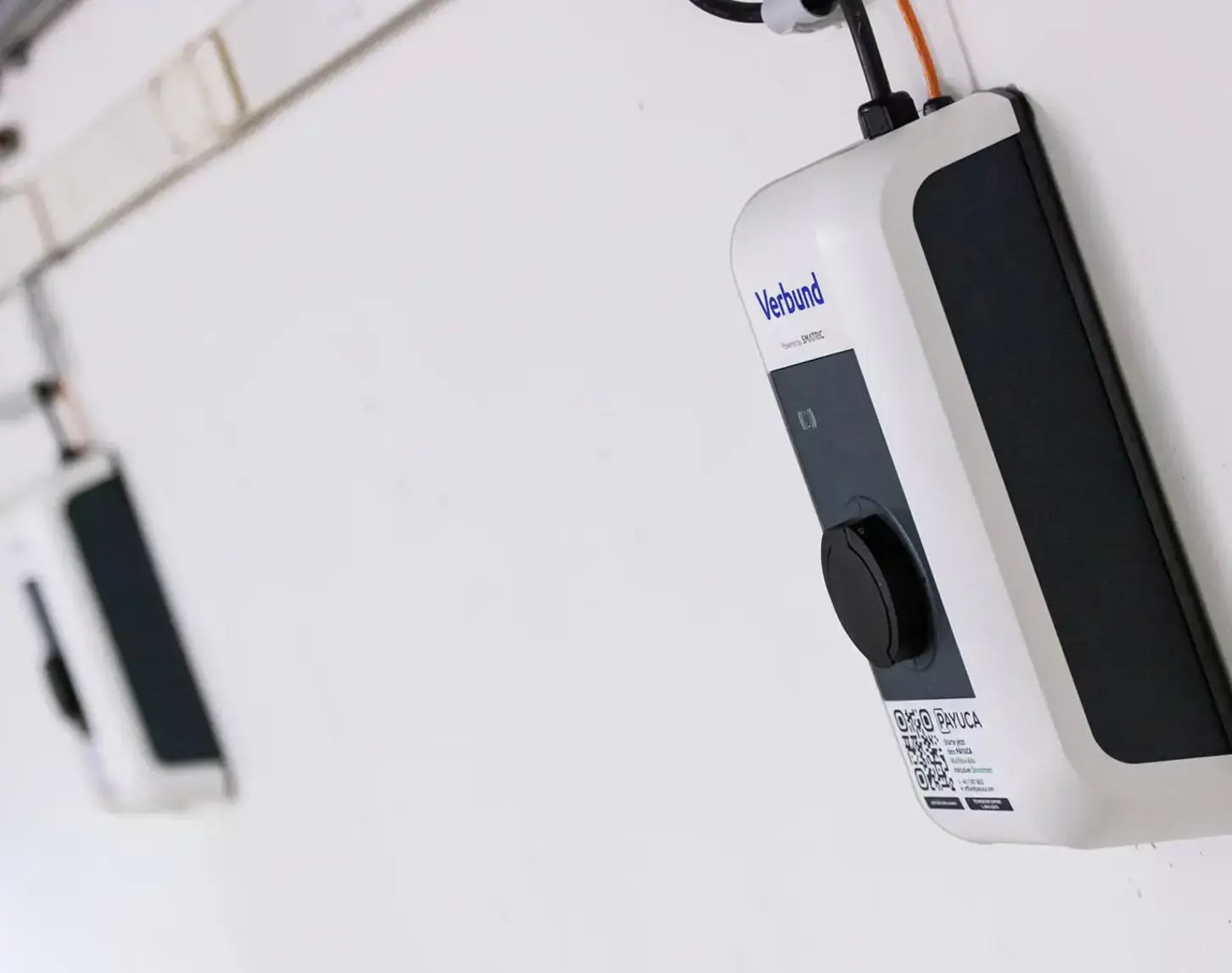 A long wall in a parking garage, featuring multiple charging points from VERBUND.