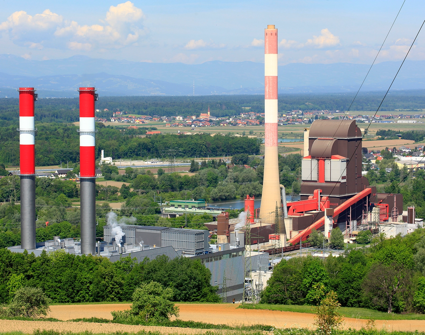 Wir blicken aus der Ferne auf das Wärmekraftwerk Mellach. Die Stimmung ist spätsommerlich. Der Himmel ist strahlend blau.