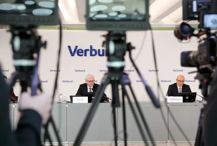 Durch die Kameras blicken wir auf Michael Stugle, CEO und Peter Kollmann, CFO von VERBUND bei einer Pressekonferenz. Wobei die Kameras in Vordergrund unscharf sind.